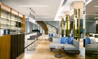 a modern hotel lobby with a bar , couches , and a staircase leading to the second floor at Radisson Lampung Kedaton