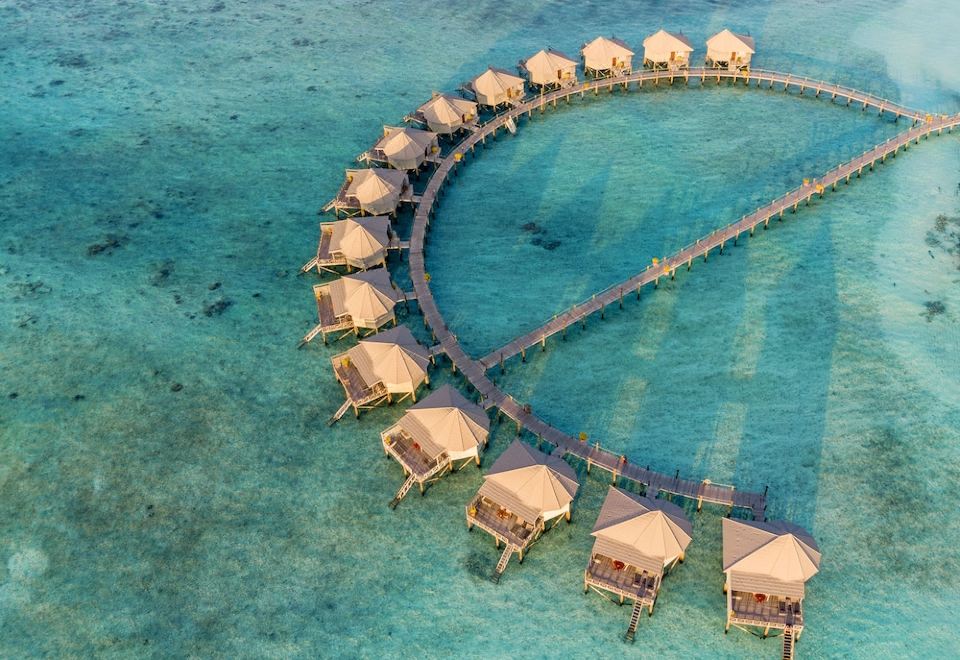 aerial view of a beach resort with many wooden huts surrounded by clear blue water at Komandoo Island Resort & Spa