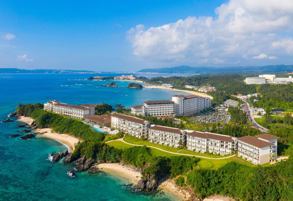 a large hotel complex is situated on the coast , surrounded by mountains and situated near the ocean at Halekulani Okinawa