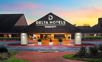 the delta hotels marriott building is shown with a sunset in the background , and several potted plants on the front of the building at Delta Hotels by Marriott Baltimore Hunt Valley