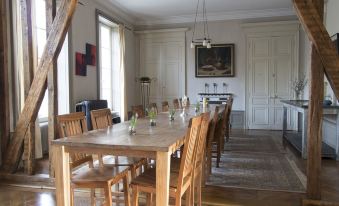a dining room with a long wooden table surrounded by chairs , and a painting on the wall at Joie de Vivre