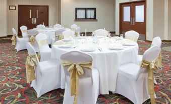 a well - decorated banquet hall with multiple tables covered in white tablecloths and adorned with gold bows at Wyndham Garden Dover