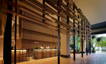 a modern building with wooden lattice screens , a reception desk , and multiple people behind the counter at PARKROYAL Penang Resort