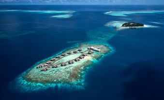 aerial view of a tropical island with multiple small islands and atolls , surrounded by blue ocean waters at Raffles Maldives Meradhoo Resort