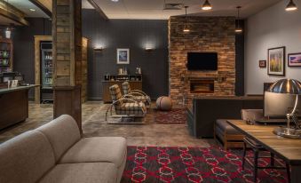 a modern living room with a brick fireplace , couches , and a tv on the wall at Four Points by Sheraton Juneau