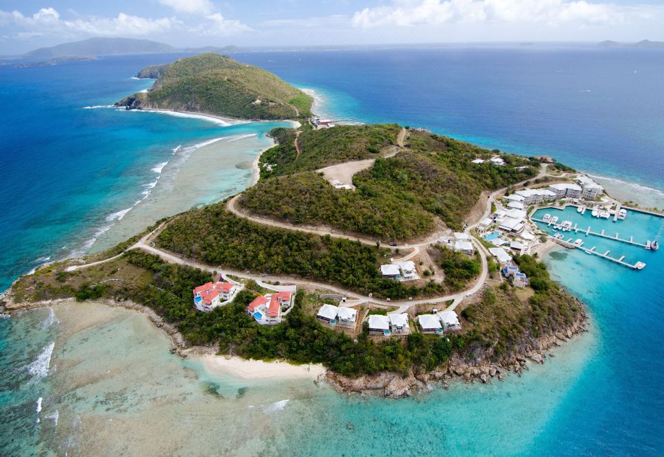 aerial view of a beautiful island with white sandy beaches , clear blue water , and green mountains in the background at Scrub Island Resort, Spa & Marina