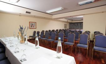 a conference room with rows of chairs and tables , water bottles , and a vase of flowers at Vila Gale Nautico
