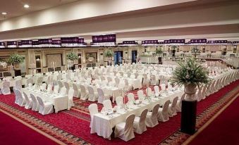 a large banquet hall with multiple tables covered in white tablecloths and chairs arranged for a formal event at Islamabad Marriott Hotel