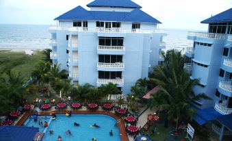 a large building with a swimming pool and people in the water are on the beach at Sanctuary Resort