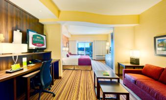 a modern hotel room with a comfortable bed , desk , and chair , as well as a view of the city through a large window at Courtyard Houma