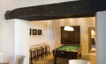 a pool table is in the middle of a room with chairs and stools around it at Parador de Argomaniz