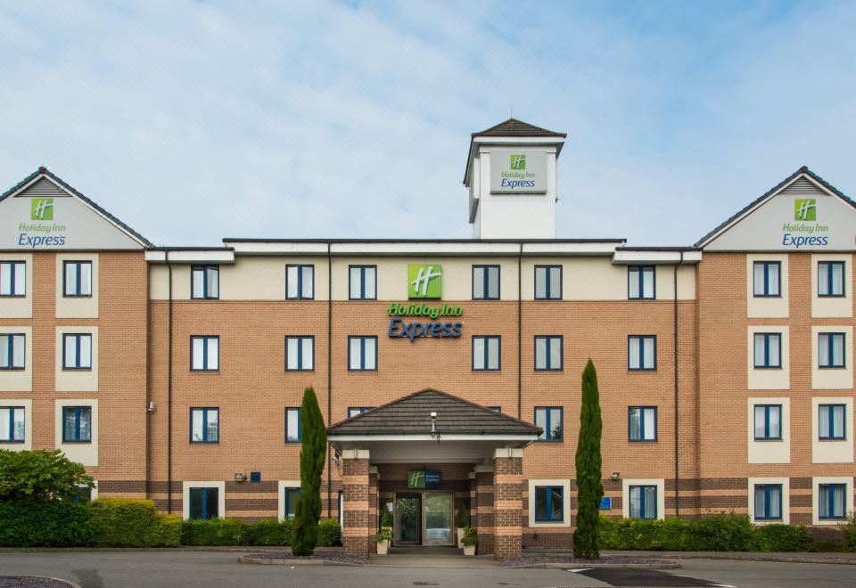 a large brick building with a green sign and a white tower , possibly a hotel or office building at Holiday Inn Express London - Dartford