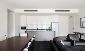 a modern living room and dining area with a large dining table , couches , and a kitchen in the background at Knightsbridge Canberra