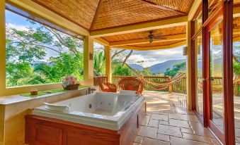 a hot tub is surrounded by a wooden deck with a view of the mountains at Sleeping Giant Rainforest Lodge
