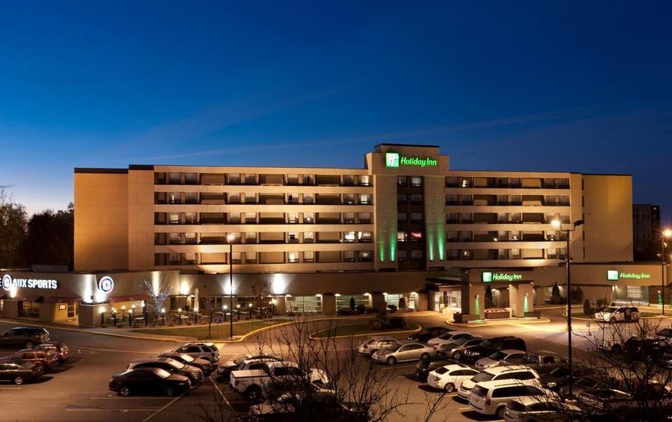 "a large hotel with multiple buildings , including one labeled "" holiday inn express ,"" surrounded by parked cars and illuminated at night" at Holiday Inn Laval - Montreal