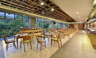 a large dining area with wooden tables and chairs , as well as a buffet table filled with food at FamVida Hotel Lubuklinggau Powered by Archipelago