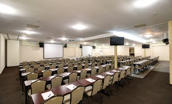 an empty conference room with rows of chairs and tables , a projector screen , and a screen at the end of the room at Hotel Dixon