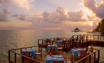an outdoor dining area with tables and chairs overlooking the ocean , creating a serene atmosphere at Coco Bodu Hithi