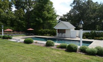 a large pool surrounded by lush green grass , with a gazebo in the background at Woodville Bed and Breakfast