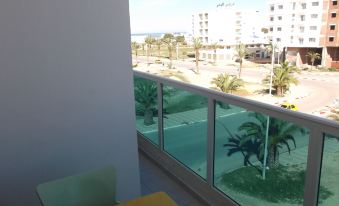a balcony with a view of palm trees and a beach , under a clear blue sky at Rahma