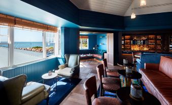 a cozy living room with blue walls , wooden floors , and various seating options , including couches , chairs , and a bar at Anchorage Port Stephens