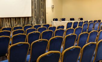 a conference room with rows of blue chairs and a white table in the center at Arklow Bay Hotel