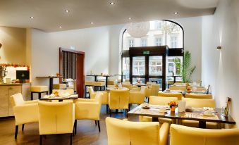 a dining room with yellow chairs and tables , creating a warm and inviting atmosphere for guests at Hotel National
