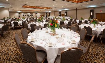 a large banquet hall filled with round tables and chairs , ready for a formal event at Holiday Inn Manitowoc