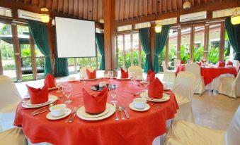 a table is set with a red tablecloth and white plates , ready for a formal dinner at Lorin Dwangsa Solo Hotel