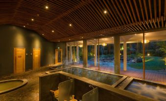 a large indoor pool area with multiple hot tubs and a wooden ceiling , surrounded by chairs at Alba Wellness Resort by Fusion