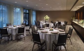 a conference room with tables and chairs , a vase of flowers , and large windows , set for a meeting at Courtyard LaGrange