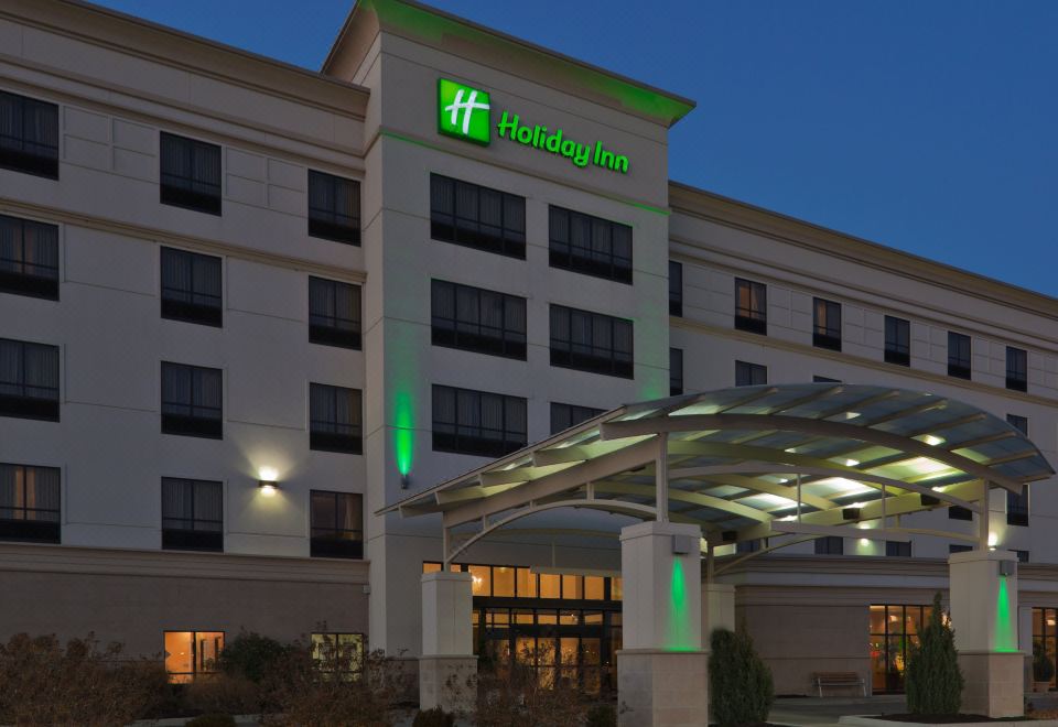 a large hotel with a green logo on the side of the building at night at Holiday Inn Carbondale-Conference Center