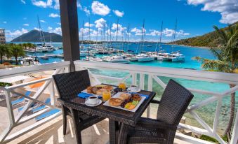 a balcony overlooking a body of water , with a dining table set for breakfast on the balcony at Scrub Island Resort, Spa & Marina