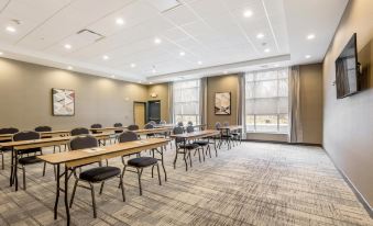 a large conference room with multiple tables and chairs , a painting on the wall , and windows at Four Points by Sheraton Elkhart