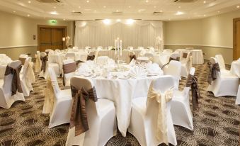 a large dining room with white tablecloths , chairs , and centerpieces , ready for a formal event at Holiday Inn Glasgow - East Kilbride