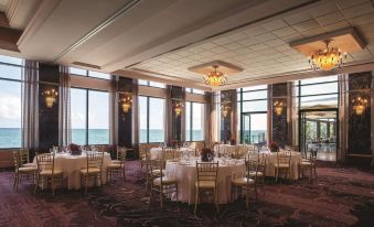 a large dining room with round tables and chairs arranged for a formal event , overlooking the ocean at Condado Vanderbilt Hotel