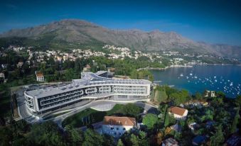 a large hotel complex surrounded by a body of water , with mountains in the background at Sheraton Dubrovnik Riviera Hotel