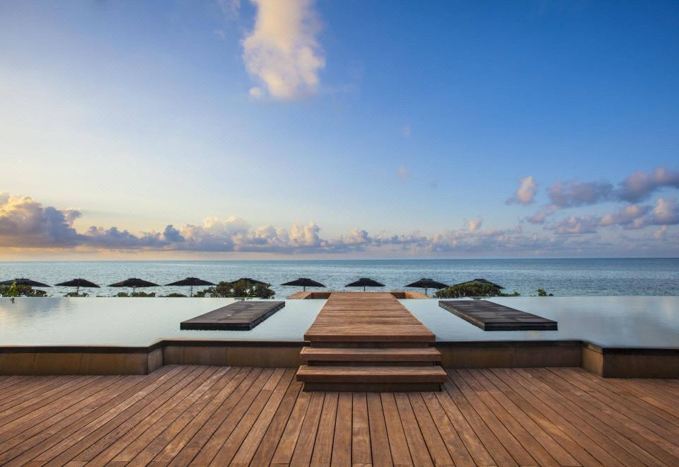 a wooden deck with umbrellas and a view of the ocean , under a clear blue sky at Nizuc Resort & Spa