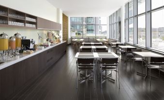 a modern cafeteria with wooden tables , chairs , and a long counter filled with various food items at Element Vancouver Metrotown