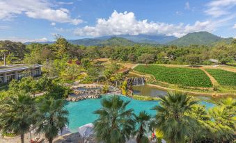 a resort with a large pool surrounded by palm trees and mountains in the background at Gran Melia Arusha