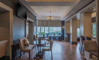 a spacious , well - lit living room with wooden floors and large windows , featuring comfortable seating arrangements and a dining area at Bunratty Castle Hotel