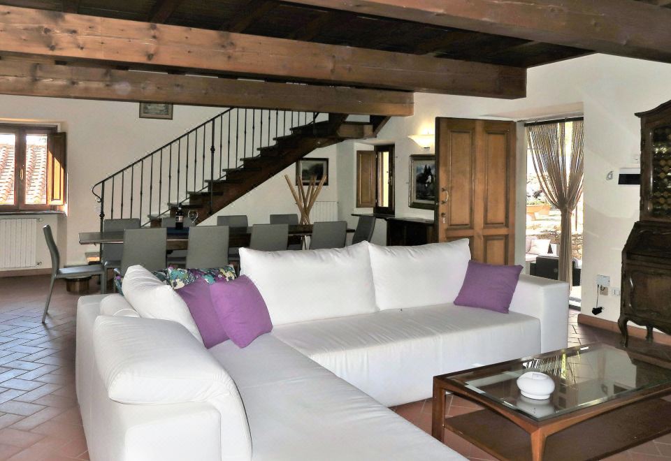 a large white couch with purple pillows is in a living room with wooden beams and a staircase at Villa