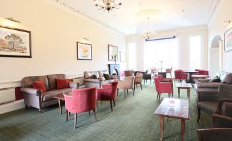 a large room with various seating arrangements , including couches and chairs , as well as a fireplace at Columba Hotel Inverness by Compass Hospitality