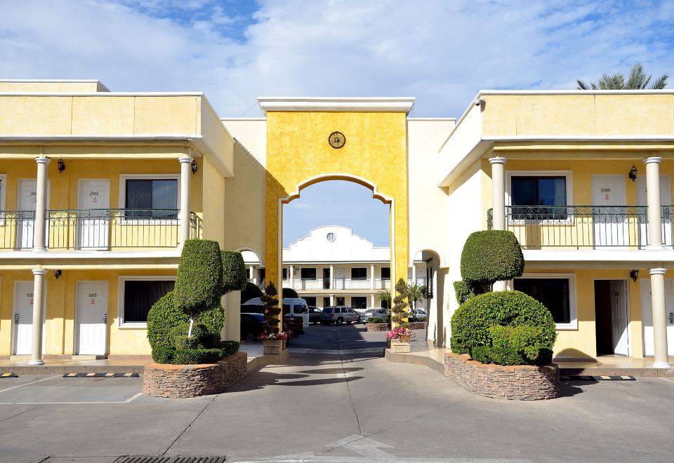 a large yellow building with a white roof and two green bushes in front of it at Hotel San Sebastian