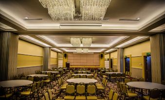a large , well - lit room with multiple tables and chairs arranged for a meeting or event at Nova Highlands Hotel