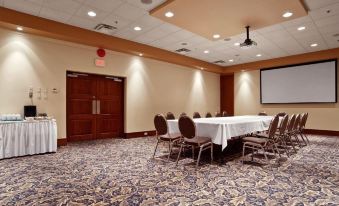 a large conference room with several chairs arranged in a semicircle around a table , and a projector mounted on the wall at Best Western Plus Barclay Hotel