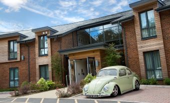 a green volkswagen beetle car is parked in front of a building with a large window at Sandford Springs Hotel and Golf Club