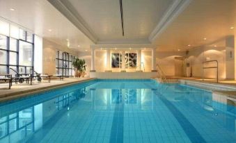 an empty indoor swimming pool with blue water , surrounded by white walls and a tiled floor at Hyatt Regency Birmingham