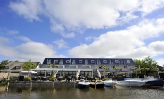 a row of boats are docked at a marina next to a building with blue skies in the background at Fletcher Hotel Restaurant Loosdrecht-Amsterdam