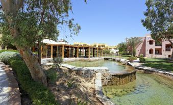 a large body of water with a stone basin and a covered area in the background at Three Corners Rihana Resort El Gouna